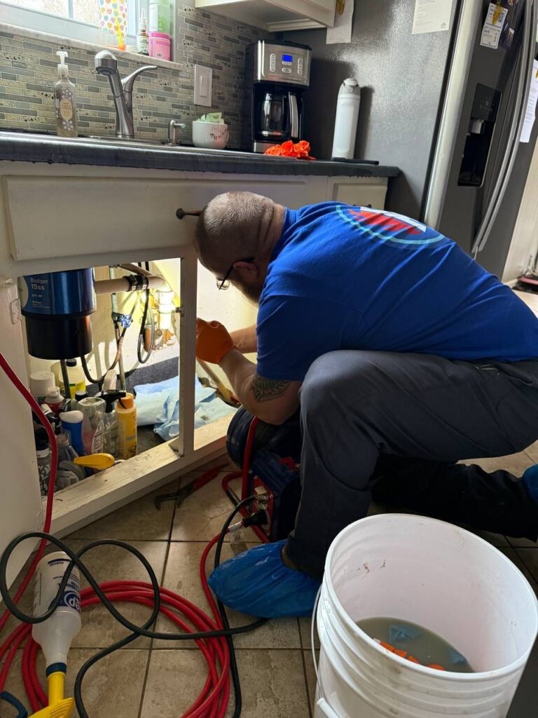 Plumber working under a kitchen sink during an emergency call in Dayton, Ohio